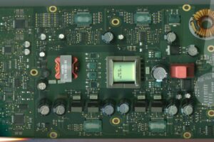 Wnętrze wzmacniacza Dynaudio AMP600 z widoczną płytą główną i komponentami elektronicznymi. To tutaj dochodzi do uszkodzeń powodujących brak dźwięku w Volkswagenie.