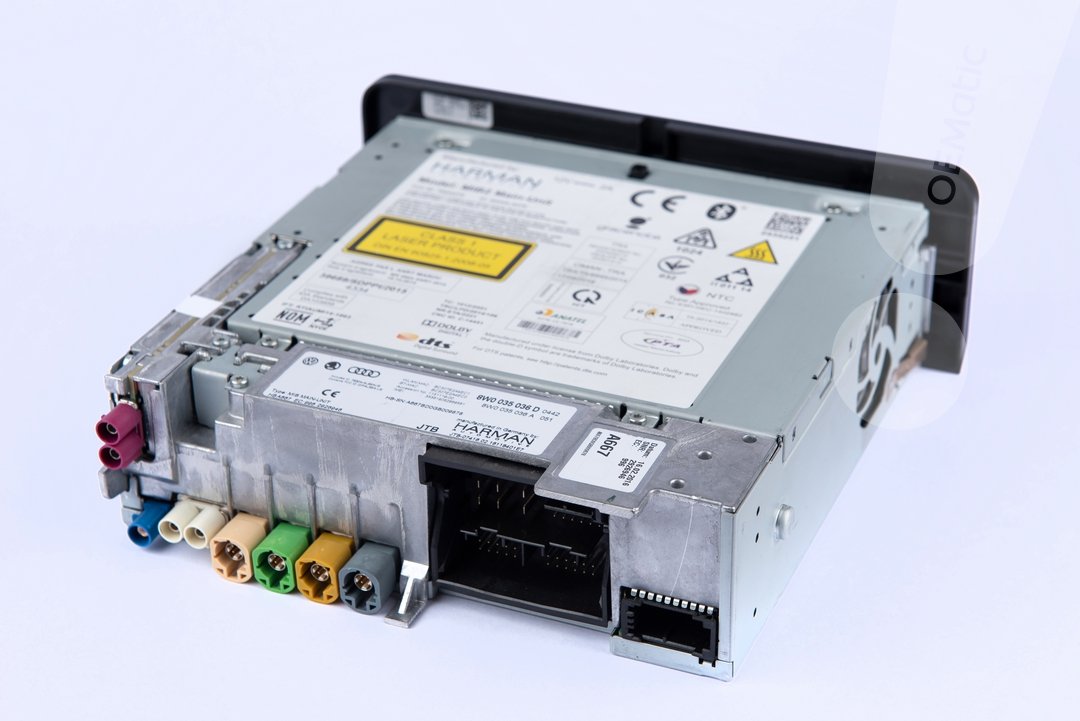 Tylna część jednostki MIB Harman Becker z widocznymi złączami audio (kolorowe wtyczki), napędem CD, slotami SD1/SD2, głównym złączem Quadlock i naklejką identyfikacyjną z numerem katalogowym